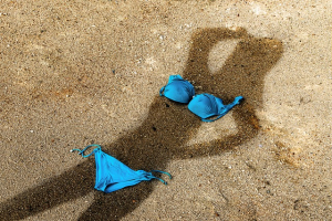 Bikini on the sand over a woman's shadow